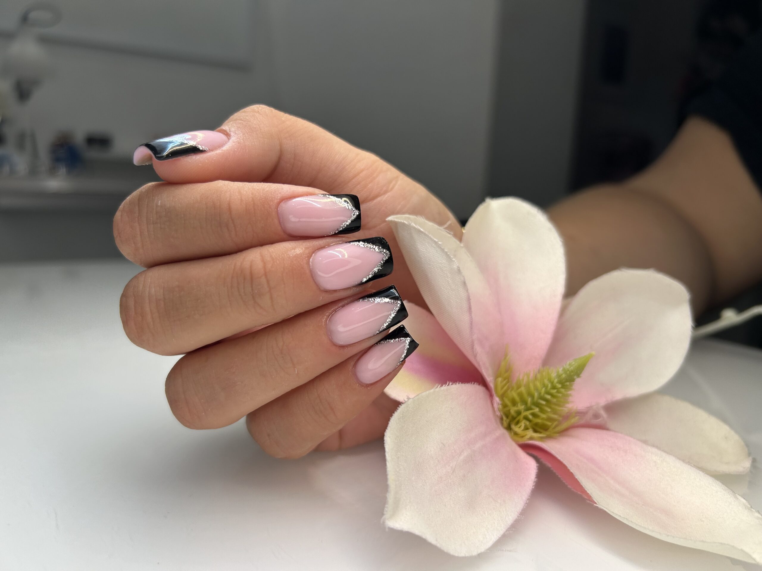 Różowe paznokcie z ciemnym frenchem i kwiatem magnolii — stylizacja Atelier Monique