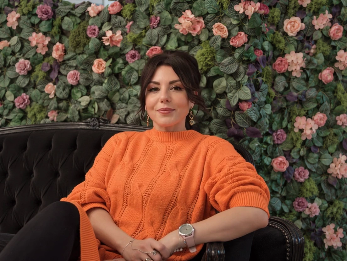 Monika Totoń w swoim atelier, na tle kwiatowej ściany